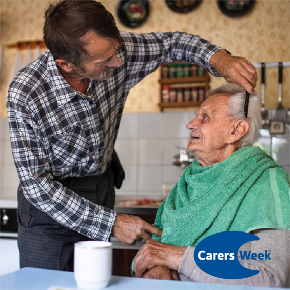 Photo of son cutting his elderly father\\\'s hair as a carer
