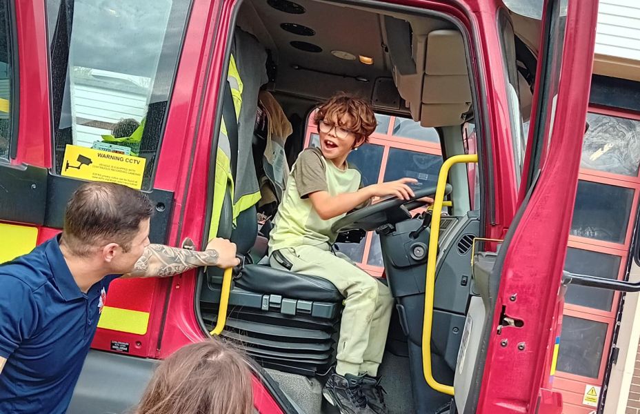 photo of a boy sitting in the cab of a fire engine