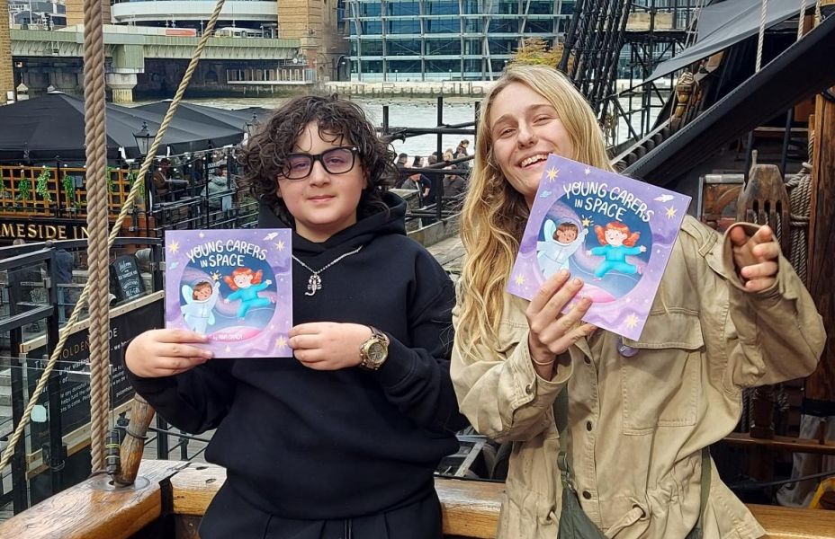 two young carers holding up the new book 