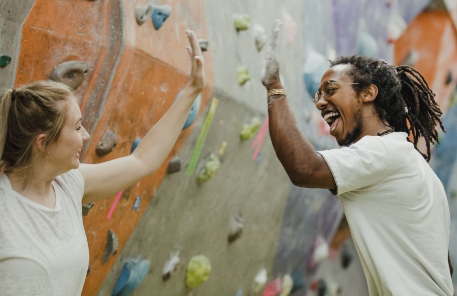 young man and woman high-fiving in front of an indoor climbing wall