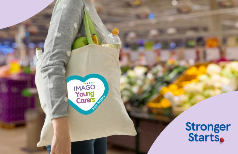 Female shopper with canvas shopping bag over her shoulder with the East Sussex Young Carers logo on it is in a supermarket with fresh fruit and vegetables on sale behind her. Stronger Starts logo on the image.