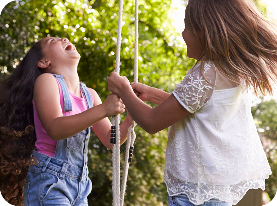 photo of two girls playing on a swing in the park
