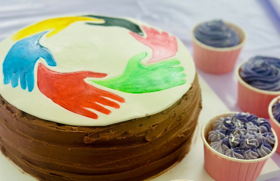 Chocolate cake with Carers Week design on the top next to cupcakes