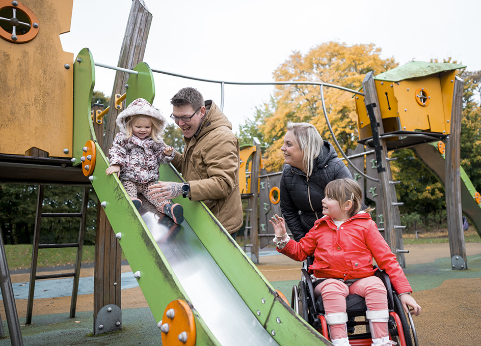 Photo of a family playing on the slide in a park